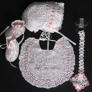 WHITE RAYON WITH EMBROIDERED PINK FLOWER EMBELISHMENT.  SET INCLUDES BOOTIES, HAT, PACIFIER HOLDER, BIB.