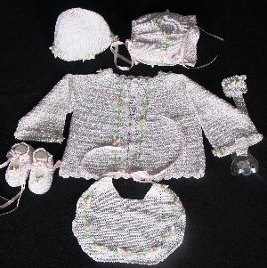 WHITE RAYON WITH TINY PINK DAISIES.  SET INCLUDES; BOOTIES, CHOICE OF TWO HATS, PACIFIER HOLDER, BIB, SWEATER.