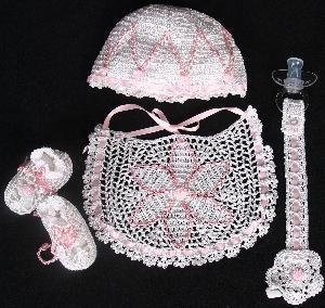 WHITE RAYON WITH PINK STAR AND TINY POM POM.  SET INCLUDES BOOTIES, HAT, PACIFIER HOLDER, BIB.