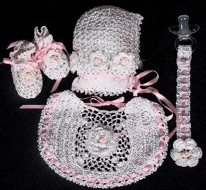 WHITE RAYON EMBELISHED WITH WHITE CROCHET FLOWERS WITH PINK ROSEBUD CENTERS.  SET INCLUDES BOOTIES, HAT, PACIFIER HOLDER, BIB.