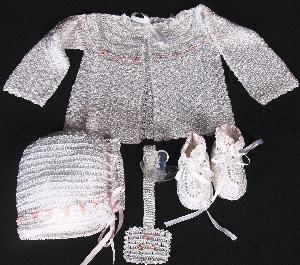 WHITE RAYON WITH TINY PINK TULIPS AND GREEN LEAVES.  SET INCLUDES; BOOTIES, HAT, BIB, PACIFIER HOLDER, SWEATER.  COULD BE WORN WITH DIAPER COVER OR PANTYLOON.
