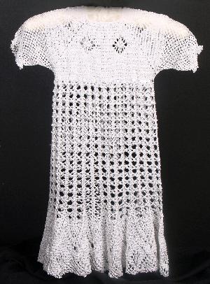 WHITE RAYON CROCHET WITH FILET CROCHET TRIM.  AVAILABLE IN WHITE OR IVORY.  THIS IS ANOTHER EXAMPLE OF ANTIQUE STYLE WITH RIBBON TO EXTEND THE LIFE OF THE GOWN.  THIS COULD BE GATHERED UP AT BODICE, SLEEVES AND NECK FOR ACHRISTENING GOWN AND IS WORN HERE BY A SIZE 5.  COULD ALSO ADD PANTYLOONS.