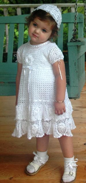 WHITE RAYON DRESS WITH ROWS OF FLOUNCE AND CROCHET ROSETTES.  RIBBONS MAKE THIS ONE OF OUR DRESSES THAT WILL FIT UP TO 6.  WEAR OVER PANTYLOONS TO EXTEND WEARING TIME.   